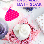 A jar of oat and lavender bath soak is nestled in pink shredded paper, with lavender sprigs and a heart-patterned gift box nearby. Text reads "Easy Gift! Oat Bath Soak.