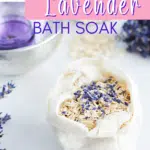 A cloth bag containing an oat bath soak with oatmeal and lavender rests on a white surface. Nearby, dried lavender sprigs accompany a small bowl holding a purple item. Text reads, "Oatmeal and Lavender Bath Soak.